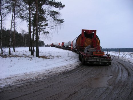Eine Lkw-Karawane fährt auf einer verschneiten Straße.
