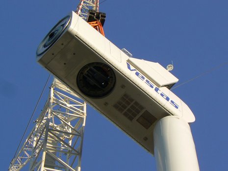 Foto von unten der Rotormontage auf der Welle einer Windkraftanlage mit einem weißen Kran.