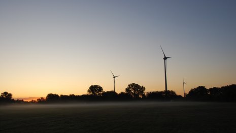 Drei Windkraftanlagen bei Sonnenuntergang