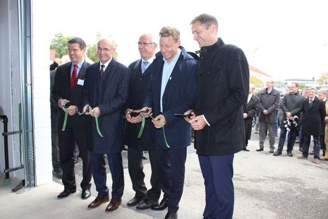 Einweihung eines Elektrolyseurs durch 5 Personen, die ein Band durchschneiden, im Hintergrund sieht das Publikum zu