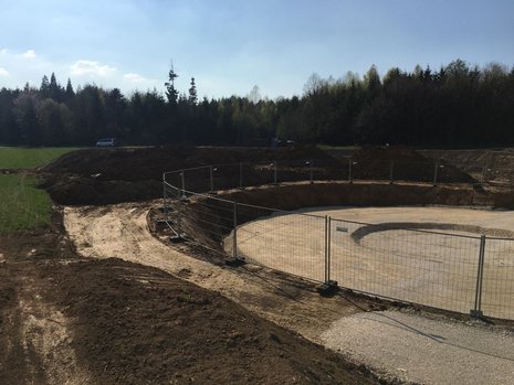 Rundes Erdloch mit umlaufendem Zaun.