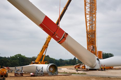 Montage des dritten Flügels an einer Windkraftanlage mit einem gelben Kran