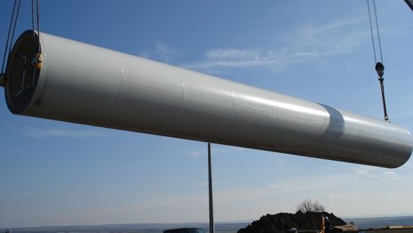Der Mast einer Windkraftanlage wird vom Boden angehoben.