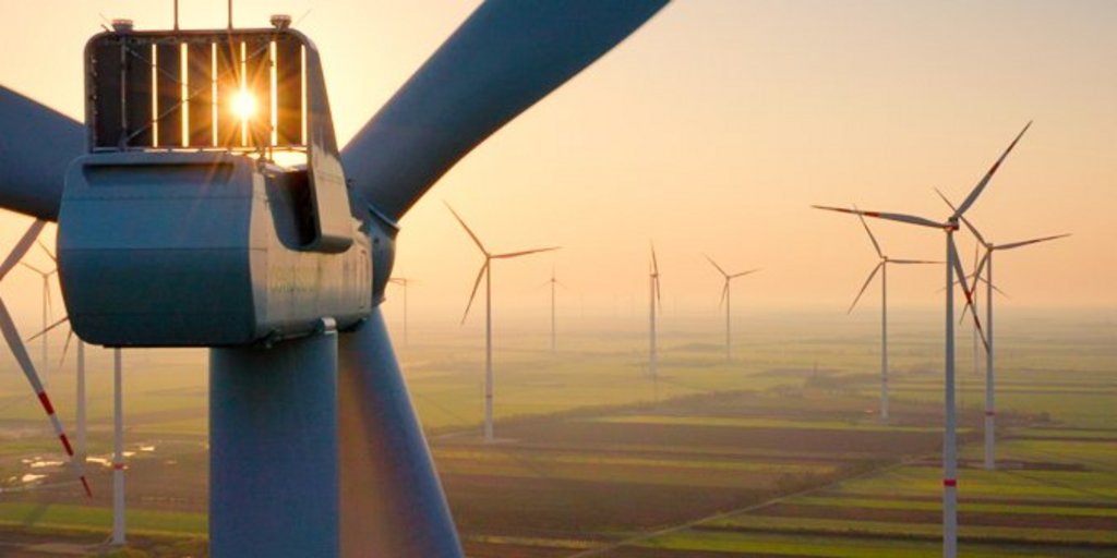 Windräder im Sonnenuntergang über einem Feld.