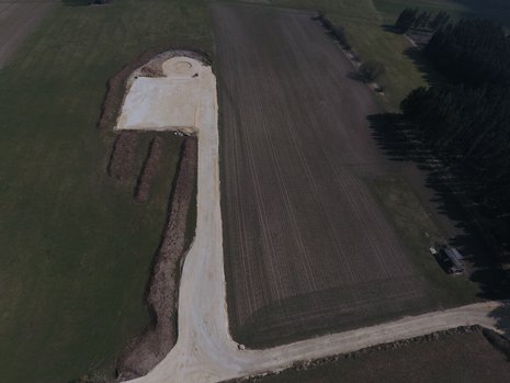 Ein Feld aus der Vogelperspektive. Das Feld ist teilweise umgegraben. Das Fundament für ein Windrad ist erkennbar.