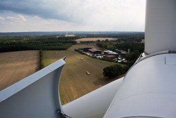 Aussicht von einer Windkraftanlage über Felder, Hofgebäude und landwirtschaftliche Landschaft.