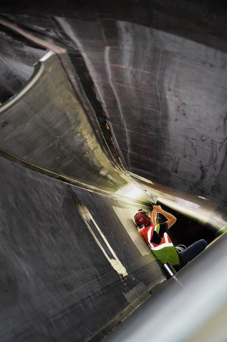 Arbeiter schließt Kabel im Inneren eines Windradflügels an.
