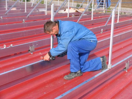 Arbeiter montiert Schienen auf rotes Dach