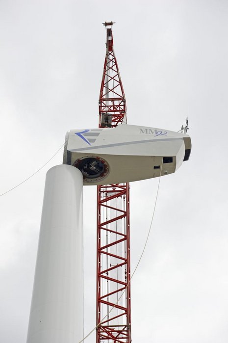 Der Rotor einer Windkraftanlage wird mit einem Kran auf den Mast montiert.