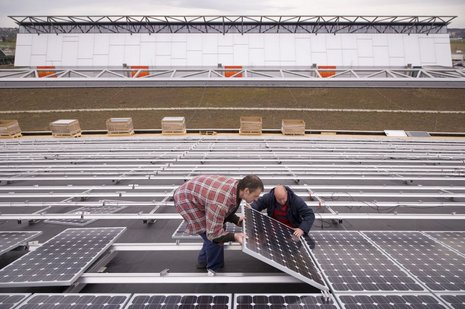Zwei Personen setzen ein Photovoltaikmodul in eine Halterung.